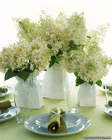 Vases of varying sizes, shapes, and materials can be unified with mere paper bags to serve as fresh, bright centerpieces at a casual shower. Slip the plain white lunch bags over the containers and cinch the tops loosely with ribbons tied in bows. (marthastewartweddings.com)