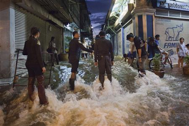 Police officers wait to assist residents passing through flood waters in Bangkok's Chinatown, 29 October 2011. Adrees Latif / REUTERS