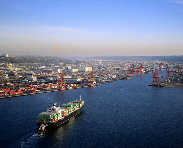 Aerial view of a cargo ship entering the Port of Seattle. Mount Rainier is visible on the horizon. Corbis