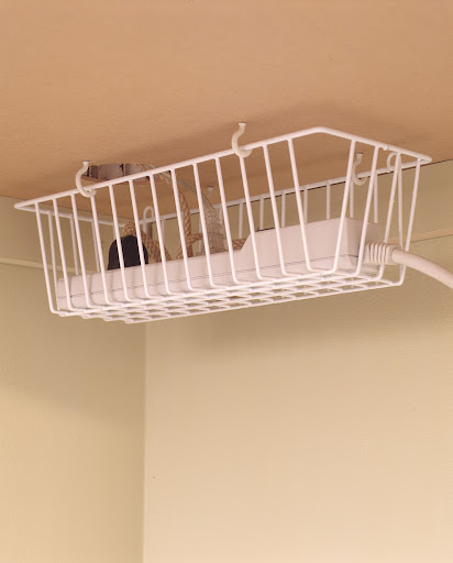 When attached to the underside of a desk, a kitchen basket is perfect for corralling cords.