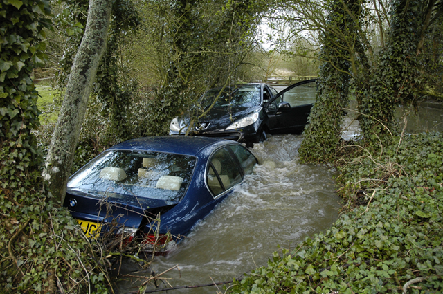 Cars swept downstream after heavy rain, near the ford across a tributary of the River Bain, Goulceby, Lincolnshire, 4 April 2012. The ford — some distance behind the black Peugeot in this picture — usually is about 4 inches deep. The year 2012 saw the wettest British spring since records began. Paul Stainthorp / flickr