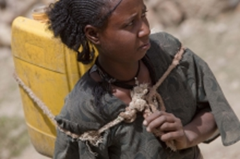 A  woman carrying water home from an almost dry riverbed during a drought. Photo: Giulio Napolitano / FAO