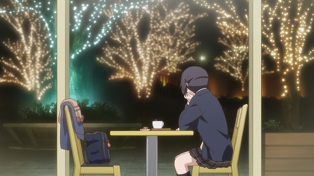 A horizontal shot of Iori sitting alone at night at a cafe table with tea and her coat and bag on the chair across from her as she looks out big windows at trees lined with lights