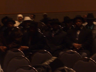 Out of focus (in a hurry) looking at a group of NOI individuals who came in a troupe, sat for a few minutes, and then walked out in a troupe.