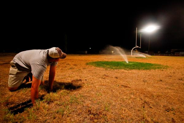 Robert Lee High School Superintendent and Athletic Director, Aaron Hood, adjusts the underground sprinkler system that is providing the life support for the school's' dried football field, 13 August 2011 10:18PM. The school waters the field nightly, putting on over 6,000 gallons a day costing $200 per load of water that is trucked in from a neighboring city. Michael Paulsen / Houston Chronicle