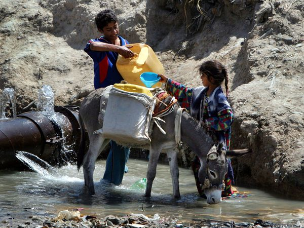 Children gather water from a broken pipe in Baghdad&rsquo;s Sadr City. Karim Kadim / AP
