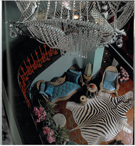 The stair hall at the James Coburn house, with a custom-made chandelier (packed with a disco ball at its center), zebra skin, antique furniture (which he bleached), with coral railings and turquoise walls.