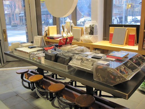 A table in the front of the store has many small accessories from wallets to color pencils, to key chains and notebooks. I love the swinging stools below the table.