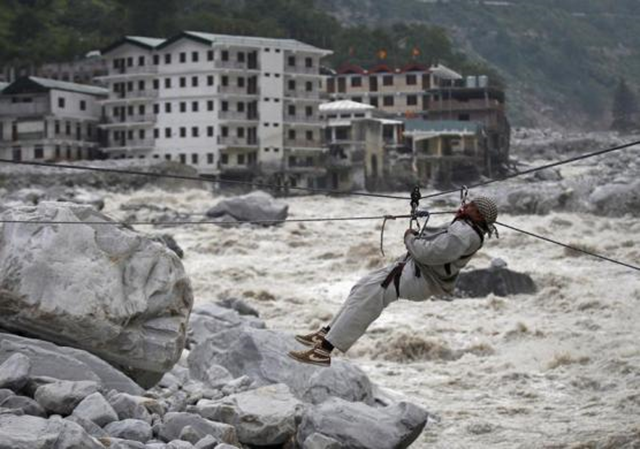 A man is pulled across to safety on a rope, as damaged buildings and the Alaknanda river are seen in the background, during a rescue operation in Govindghat in the Himalayan state of Uttarakhand, 23 June 2013. Photo: Danish Siddiqui / REUTERS