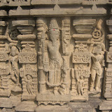 Agni, shown with beard in the central niche. He is shown with four hands, carrying sruk (spoon), vedas (books), akshamala and kamandalu. The image seems to be tried to be accommodated into the small space of the niche, so many of its characteristics are not very clear.