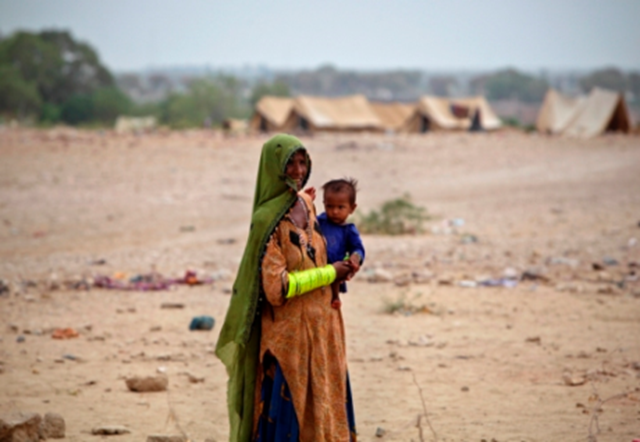 Hurmi, 35, who has been displaced by heavy floods for almost a year, holds her child near makeshift shelters along a road in Jamshoro, some 150 km (93 miles) north of Karachi, Pakistan, 25 July 2011. Akhtar Soomro / REUTERS