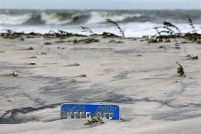 A 'Keep off the dunes' sign is buried in Cape May, New Jersey, after a storm surge from hurricane Sandy, 31 October 2012. Photo: acecabana