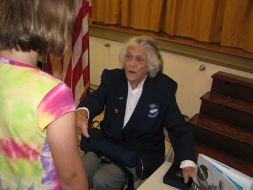 A young girl talks with Young after the assembly;  Young was six years old when she saw her first airplane. It was made of a wood frame and was covered in canvas.