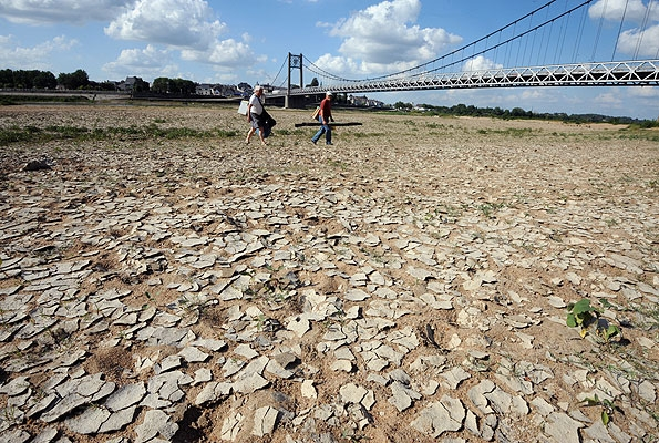 People walk across a dried riverbed in France. The spring of 2011 was France's driest in decades and hottest in a century, drying up reservoirs and killing crops. FRANK PERRY / AFP / Getty Images