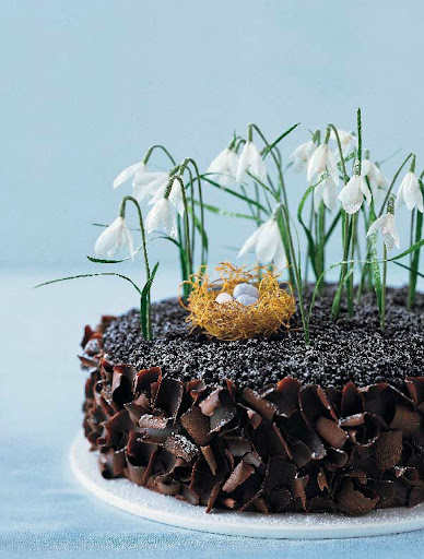 Crafted out of crepe paper, these dainty snowdrops crown a decadent soil—chocolate cake.
