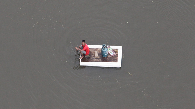A Thai flood victim on a raft uses a paddle to collect relief supplies dropped from a Thai military helicopter in Pathum Thani province, north of Bangkok, Thailand, on Monday Oct. 17, 2011. Sakchai Lalit / AP