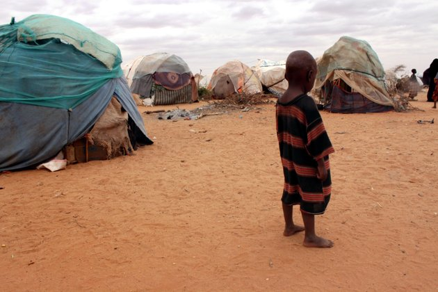 A barefoot child stands among ragged tents at a refugee camp in Dolo, Somalia on Wednesday, 18 July 2012. Photo: Jason Straziuso / AP Photo