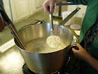 Using a slotted spoon, Monty scoops the ricotta out of the pan.
