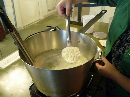 Using a slotted spoon, Monty scoops the ricotta out of the pan.