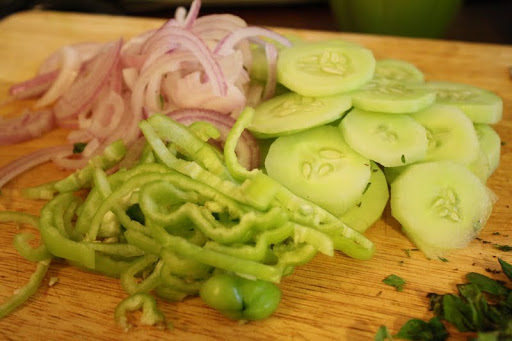 Adding the onions, cucumbers, and peppers, and chopping the herbs for the buttermilk vinaigrette.