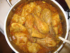 The roasted chicken is added to a skillet with spices, onion, tomatoes, ginger, garlic, and the reserved marinade.