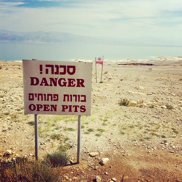 A sign near the Dead Sea reads, 'Danger! Open Pits'. More than 3,000 sinkholes have formed on the banks of the receding Dead Sea, as people divert water from the Jordan River. Photo: Molly Hunter