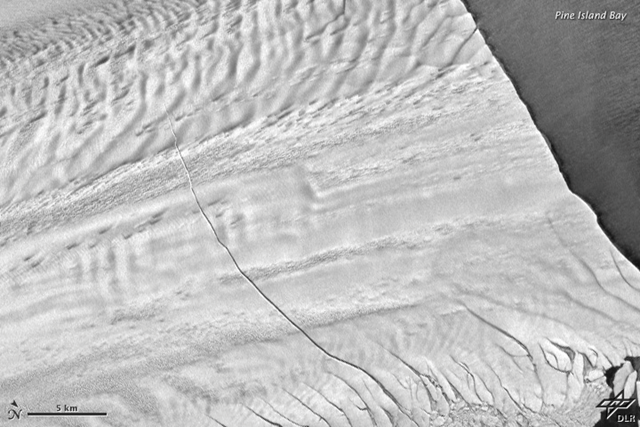 Aerial view of a crack in Pine Island Glacier, 31 October 2011. The massive rift runs about 29 kilometers (18 miles) across a part of the glacier’s floating tongue. The rift is 80 meters (260 feet) wide on average, and 50 to 60 meters (170 to 200 feet) deep. NASA Earth Observatory image by Robert Simmon with data from the German Aerospace Center