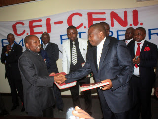 De gauche à droite Abbé Apolinaire Malu Malu et le Pasteur Ngoy Mulunda, en poignet des mains, s’échangeant des documents lors de la remise et reprise Cei-Ceni ce 3/3/2011