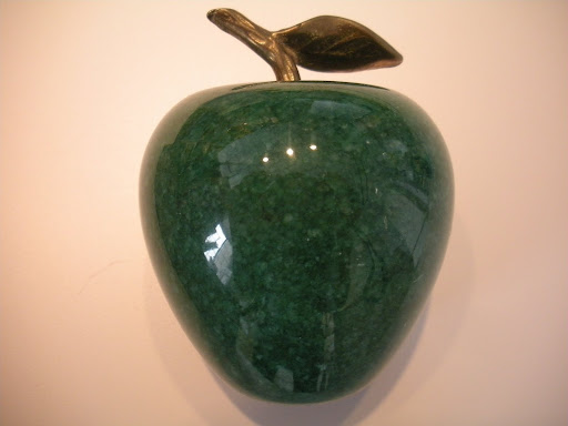 An apple paperweight with a brass leaf.
