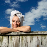 Retired woman outdoors with towel on her head.