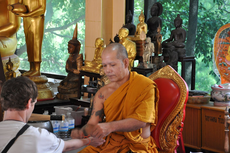 Тайский монах повязывает веревочку на руку