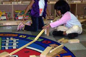 Children explore motion and force using ramps made of cove molding and marbles.