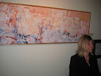 Shea Slemmer (artist and owner of Flux Gallery) at the front desk. In the background is a Christina Foard painting.