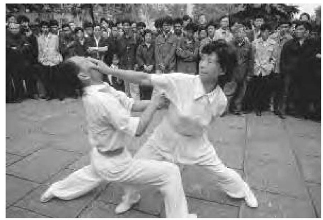 A crowd watches as a couple stages a martial arts demonstration on a sidewalk in Shanghai, October 1983.