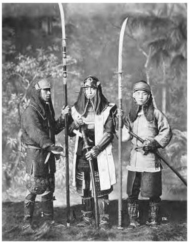 A portrait of three men in Japan dressed as samurai warriors, wearing armor and carrying naginata (halberds) and katanas (long swords), ca. 1890. 