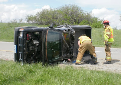 Pella firefighters pick up debris from a rollover accident