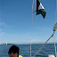 Jan at the tiller of Whisper, Harry P and Matia Island in background