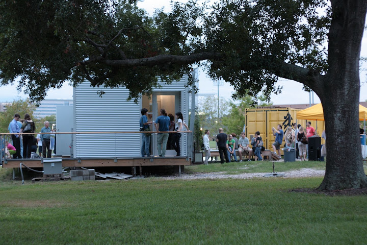 View of the backside of the ZEROW HOUSE; groups of people stand around outside enjoying the cool evening and partaking in the evening celebrations.