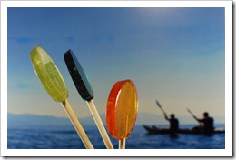 Turquose, Gold and Seafoam Green lollipops in the foreground; sea kaykers in background