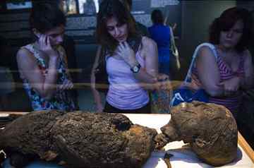 People look at the unwrapped remains of King Tut. (Associated Press)