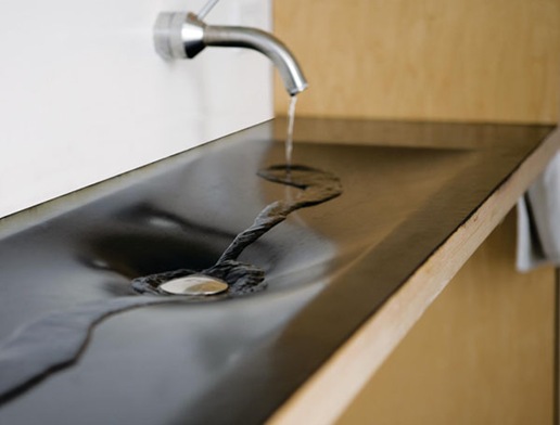 The shallow basin of the sink is formed from a sheet of rubber stretched down and held in place by the drain collar. 