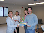 Yara Hidalgo accepts her Glow certificate, binder, and flash drive from Alana Okamoto, Rachael Brock, and Adam Marchick