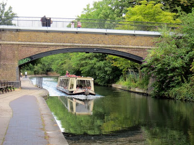 Canal boat cruising under a bridge on Regent's Canal in London