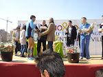 Antonio Rodrigo Torrijos entrega el galardón al ganador de la I Carrera Popular Victoria Domínguez, celebrada en el Polígono Sur.