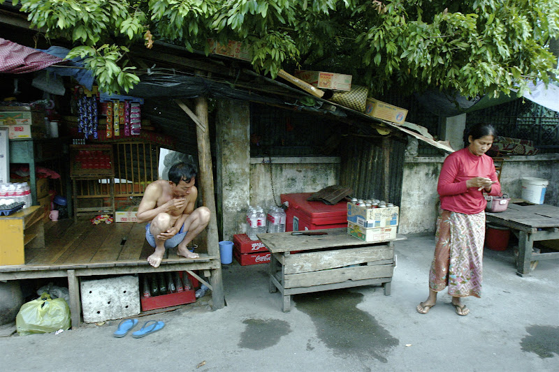 Crouching cambodian man plucking facial hair