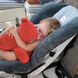 A happy baby napping in the cockpit with red bear.