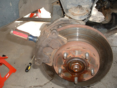 It might seem a little redneck, but take a sturdy screwdriver and stick it through the opening in brake caliper and into one of the openings along the outside of the brake rotor.  This will keep the hub from turning in the next few steps.