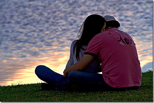 Casal vendo o sol poente no parque Casal vendo o sol poente