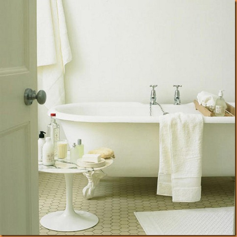 Modern home: white bathroom, roll top bath, honeycomb mosaic vinyl flooring,  round marble top table,  toiletries,  towels. Pub orig  L etc 05/2005 p118