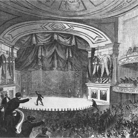 Actor and assassin John Wilkes Booth runs across the stage of Ford's Theater after having shot President Abraham Lincoln. A man climbs up on stage to pursue him.